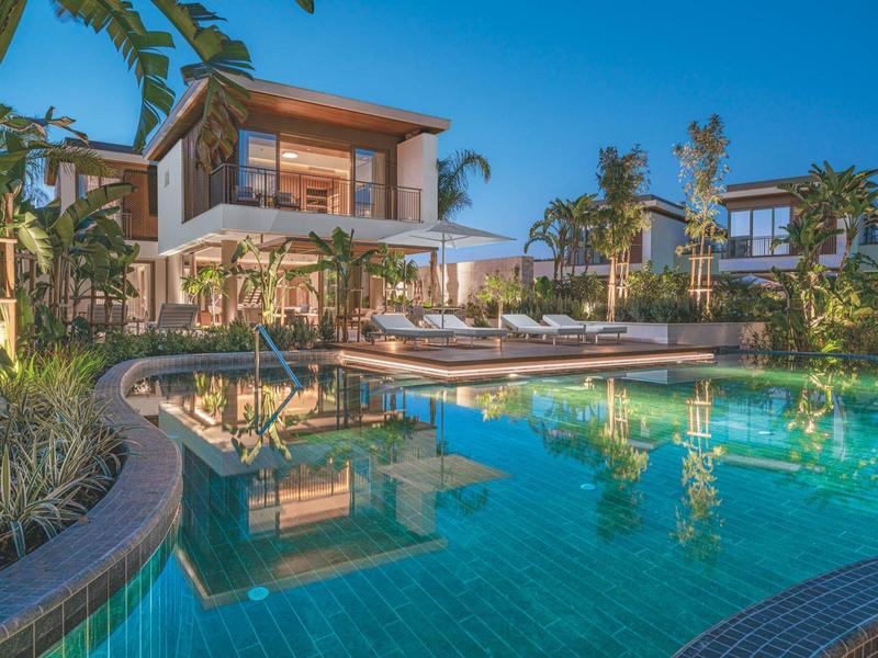 Hotel moderno con piscina illuminata e lettini in ambiente tropicale al crepuscolo