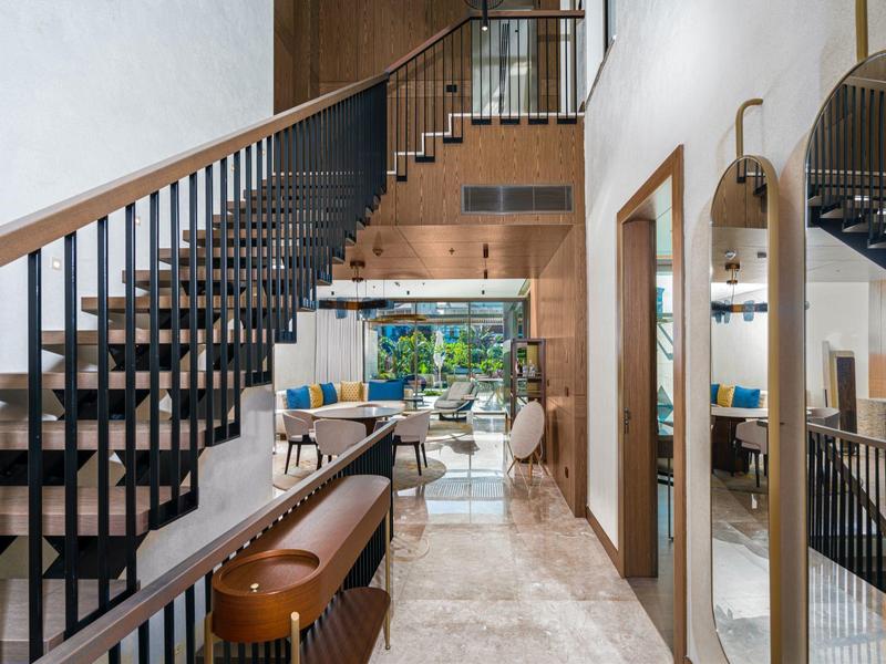 Scala interna moderna con ringhiera in metallo, soffitti alti e vista sul soggiorno.