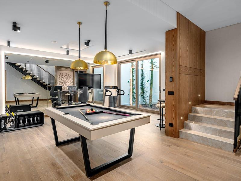 Area giochi moderna con tavolo da biliardo, design d'interni elegante e grandi finestre.