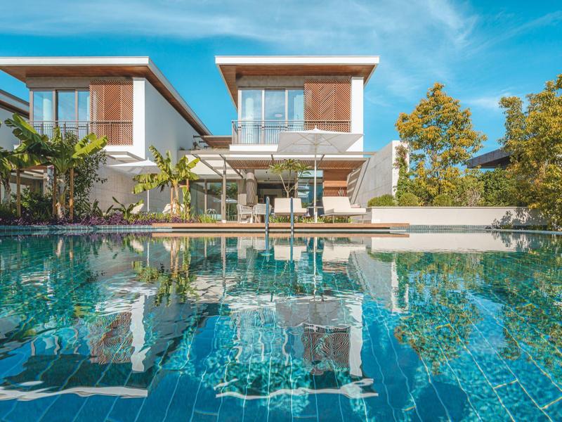 Edificio alberghiero moderno su due piani con grande piscina e ombrelloni all'aperto.