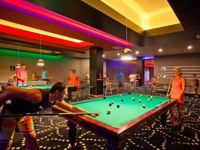 Varias personas juegan al billar en una sala de billar elegante y con iluminación moderna.