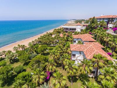 Vista de un complejo hotelero en la playa con mar, playa y vegetación abundante.