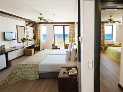 Modern hotel room with two bedrooms and sea view through large windows.