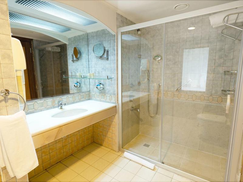 Modern bathroom with glass shower, washbasin, and illuminated mirror.