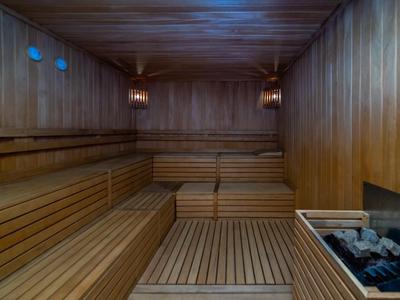 Ampia sauna in legno con panche e riscaldatore con pietre.