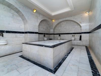 Elegante area spa dell'hotel con pareti in marmo, pavimento e vasca centrale in pietra.