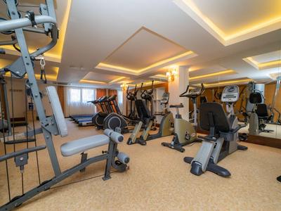 Modern ausgestatteter Fitnessraum mit verschiedenen Trainingsgeräten und warmem Licht.