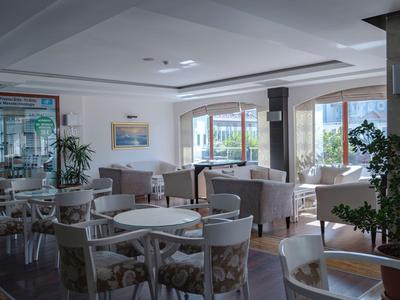 Helle Hotel-Lounge mit weißen Stühlen, Tischen und großen Fenstern mit Blick nach draußen.