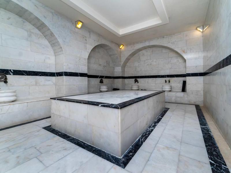 Elegante area spa dell'hotel con pareti in marmo, pavimento e vasca centrale in pietra.