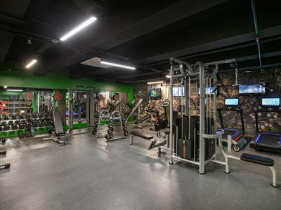 Moderní posilovna s různými tréninkovými stroji a volným prostorem na cvičení.