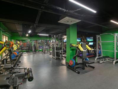 Velká posilovna s různými posilovacími stroji a činkami v moderním hotelu.
