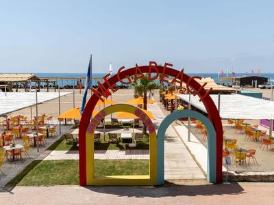 Pohled na barevný plážový bar s stoly a židlemi u moře za slunečného dne.