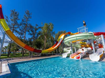 Barevné vodní skluzavky vedou do velkého bazénu pod jasně modrou oblohou.