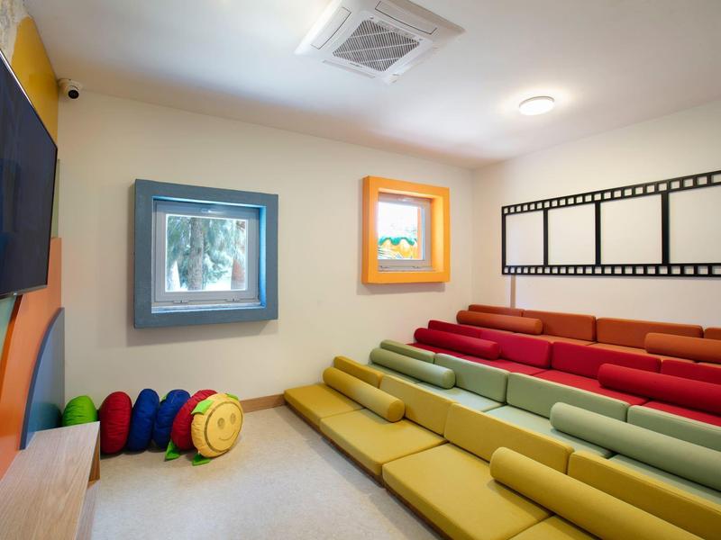 Barevná seminární místnost s vrstvenými polštáři a dekorativními rámy na stěně.