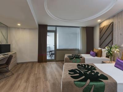 Camera d'hotel moderna con due letti singoli, pavimento in legno e scrivania con TV.