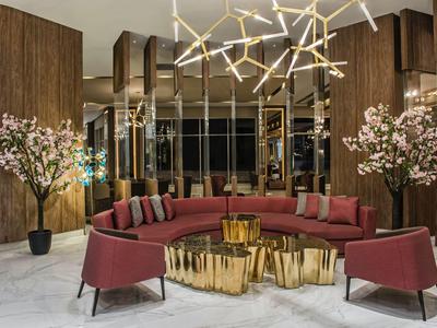 Elegant hotel lounge area with curved red sofa and gold-colored tables.