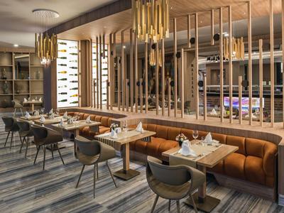 Modern hotel restaurant with wooden furniture, comfortable chairs, and stylish lighting.
