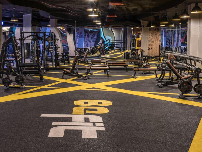 Palestra moderna con varie macchine per esercizi e pesi in una stanza ampia.