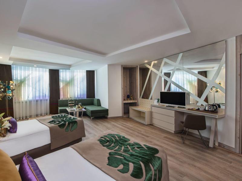 Suite d'hotel spaziosa con arredamento moderno, comodi posti a sedere e grande TV a schermo piatto.