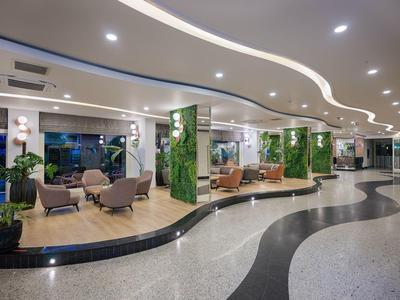 Moderner Lobbybereich mit geschwungenem Bodenmuster, Sitzgruppen und grünen Pflanzenwänden.