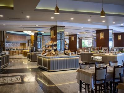 Weitläufiger, eleganter Restaurantbereich mit modernem Design, Holzsäulen und gedeckten Farbtönen.