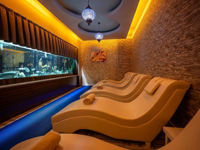 Moderner Wellnessraum mit braunen Relaxsesseln, großem Aquarium und gedämpfter Beleuchtung.