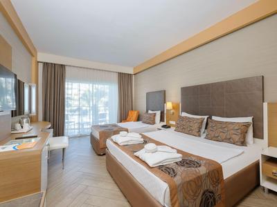 Modernes Hotelzimmer mit zwei Betten, Schreibtisch und Balkon mit Blick auf das Meer.