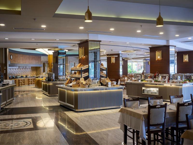 Weitläufiger, eleganter Restaurantbereich mit modernem Design, Holzsäulen und gedeckten Farbtönen.