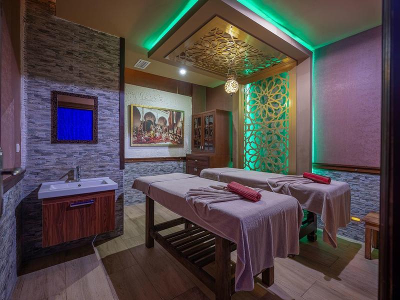 Gemütlicher Massageraum mit zwei Liegen, warmen Farben und dekorativer Beleuchtung.