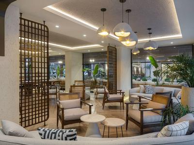 Salón moderno de hotel con cómodas sillas, mesas y luz cálida.