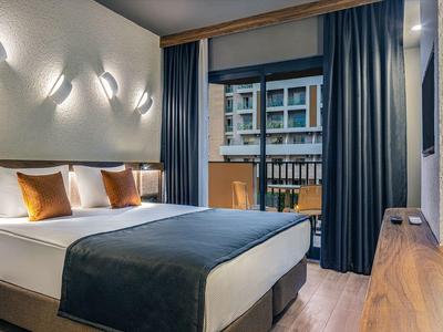 Habitación de hotel moderna con cama grande, paneles de madera y vista a la ciudad por la ventana.