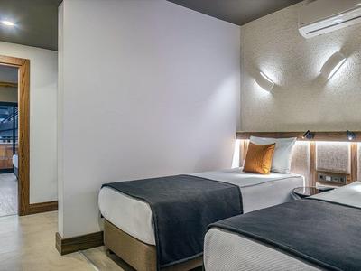 Habitación de hotel moderna con dos camas individuales y luz cálida.