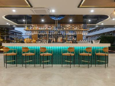 Área de bar moderno en hotel con barra iluminada y taburetes altos en ambiente claro.