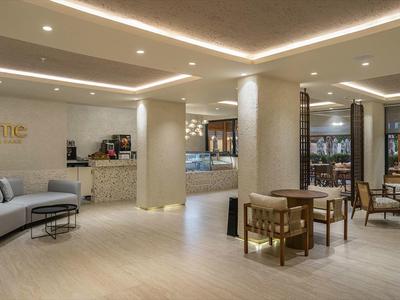 Área de vestíbulo de hotel moderno con sofás cómodos, mesas y diseño de iluminación cálida.