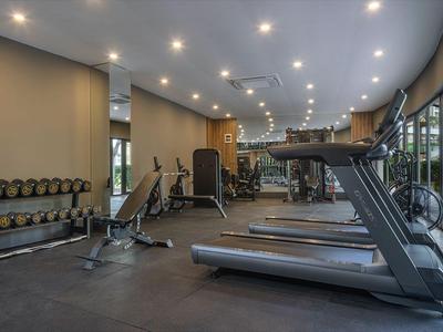 Gimnasio moderno con pesas, cintas de correr y grandes ventanas con vistas a la ciudad.