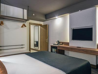 Moderní hotelový pokoj s velkou postelí, dřevěným nábytkem a minimalistickým designem.