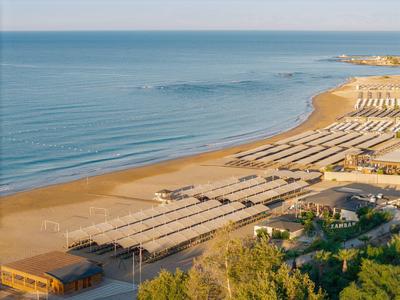 Pohled na dlouhou písčitou pláž s mnoha lehátky a slunečníky u moře.