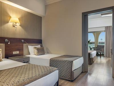 Dvě jednolůžka v hotelovém pokoji s přístupem do obývacího pokoje a výhledem na moře.