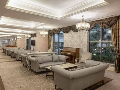 Elegant hotel lounge area with comfortable armchairs, carpeted floor, and chandeliers.