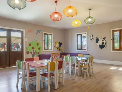 Children's room with colorful chairs, wall decorations, and wooden floor in a hotel.