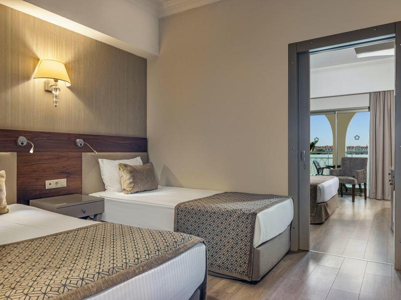 Dvě jednolůžka v hotelovém pokoji s přístupem do obývacího pokoje a výhledem na moře.