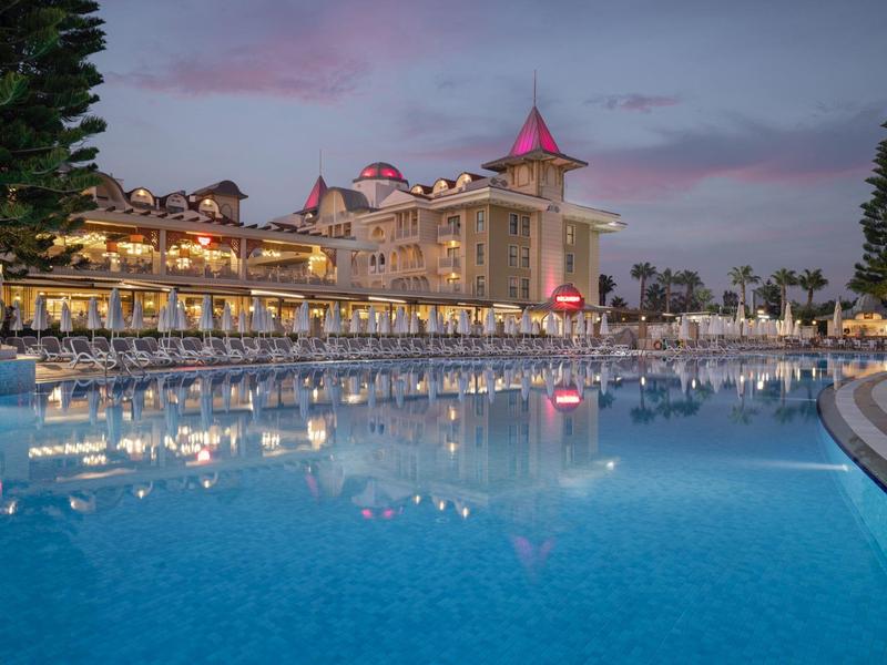 Luxusní hotel za soumraku s velkým osvětleným bazénem a lehátky