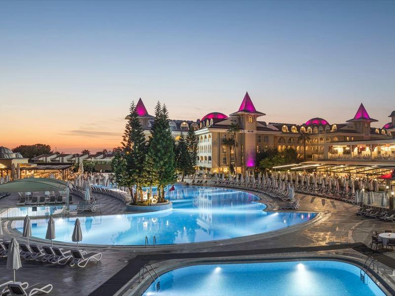 Luxusní hotel s osvětleným bazénem a posezením při západu slunce