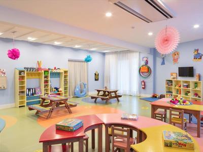 Stanza giochi colorata e ben illuminata con tavoli, sedie e giocattoli in un hotel.