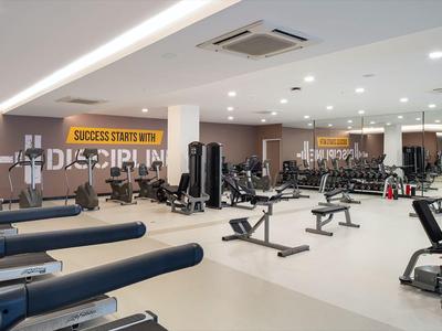 Moderner Fitnessraum mit verschiedenen Trainingsgeräten und hellen Innenräumen.