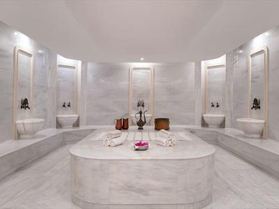 Un lussuoso hammam turco con lavandini e colonne in marmo.