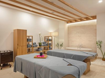 Stanza spa moderna e luminosa con due lettini da trattamento e soffitto in legno.