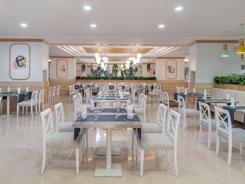 Ampia sala da pranzo luminosa con arredamento moderno e piante sulla parete.