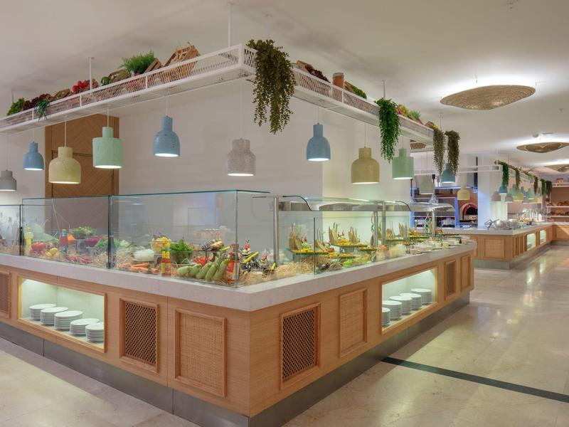 Area buffet con insalate fresche e lampade a sospensione in un ristorante d'hotel luminoso.