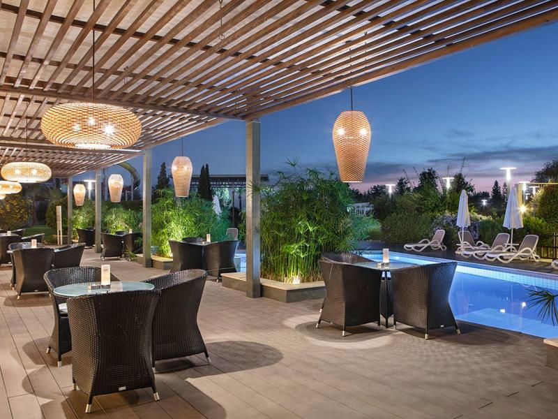 Elegante bar all'aperto con piscina e schermo di privacy piantato al crepuscolo.